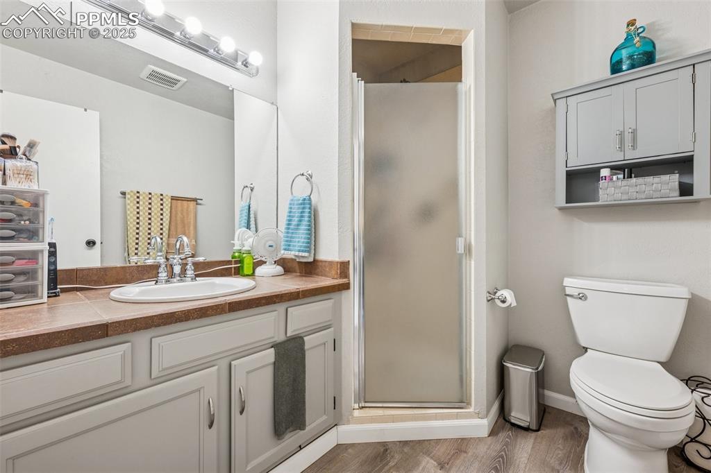 Image 6 of 25: Bathroom with a shower stall, vanity, and wood finished floors