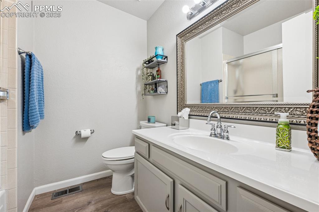 Image 7 of 25: Full bathroom with a shower stall, vanity, and dark wood-type flooring