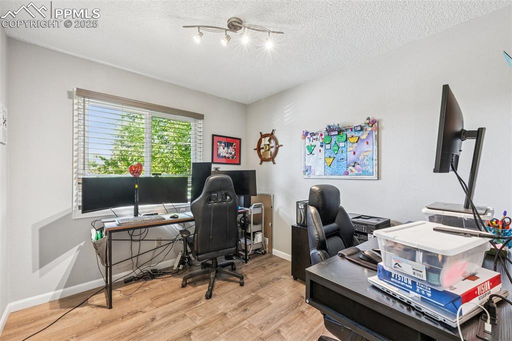 Image 8 of 25: Home office with light wood-style floors, a textured ceiling, and rail ligh
