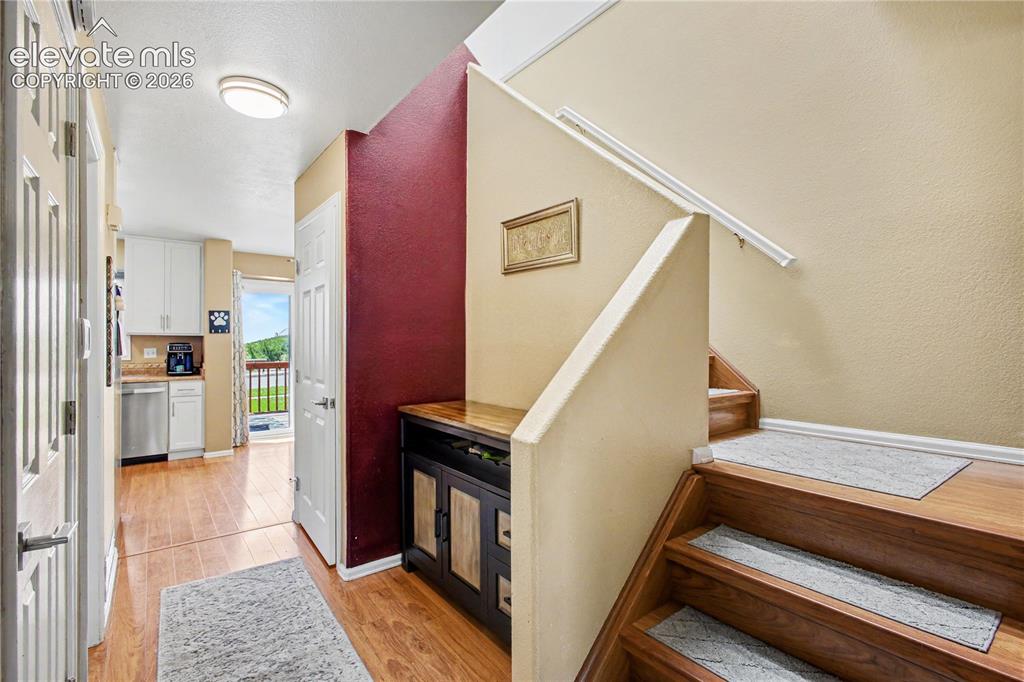 Image 6 of 25: Hall to half bath and kitchen and stairs to upper level