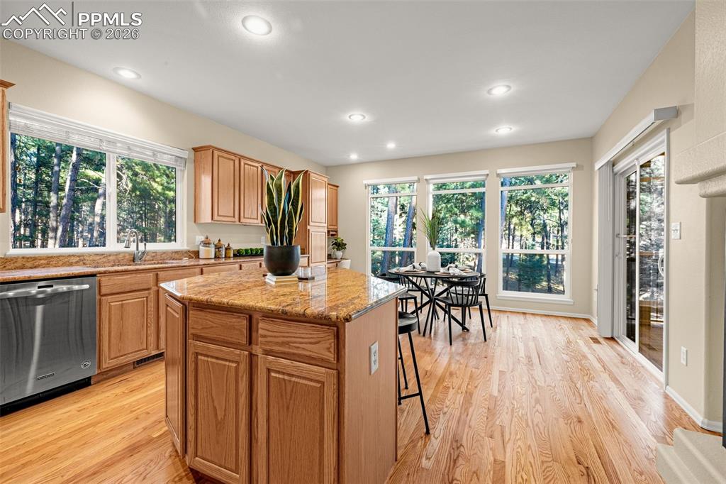 Image 11 of 40: The kitchen features hardwood flooring, wooden cabinetry, granite counterto