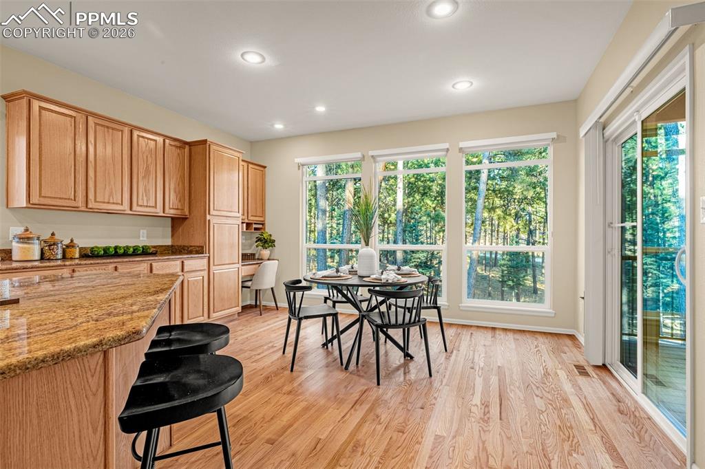 Image 14 of 40: The kitchen and dining area features hardwood flooring, wooden cabinetry, a