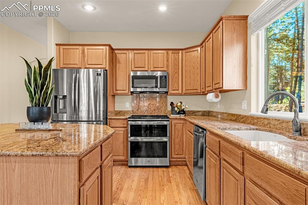 Image 15 of 40: The kitchen features light wood cabinetry, granite countertops, and stainle