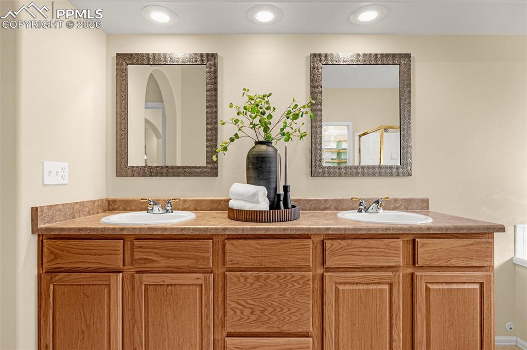 Image 23 of 40: Bathroom featuring a double vanity with light wood cabinetry, two integrate