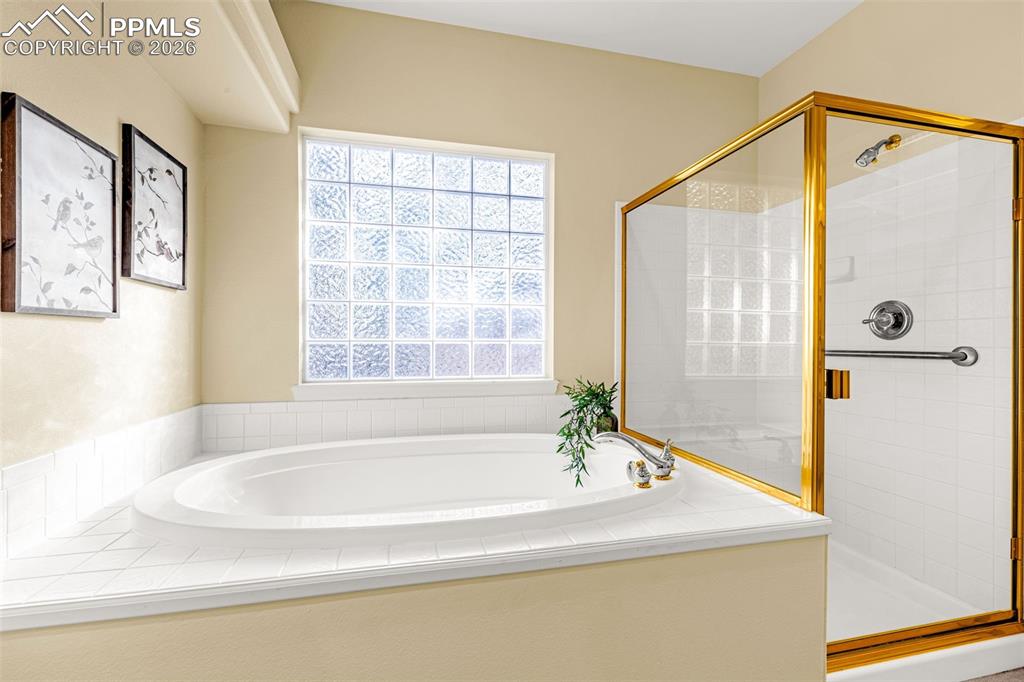 Image 24 of 40: Bathroom featuring an oval built-in bathtub, a glass block window, and a sh