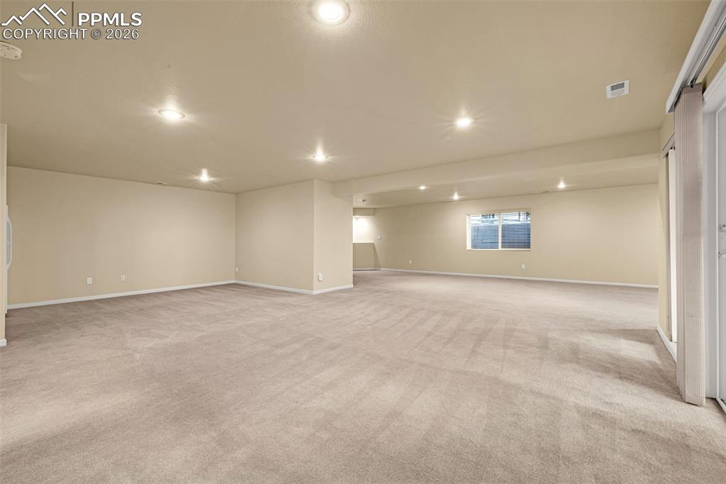 Image 28 of 40: Spacious interior room with light-colored carpeting, recessed lighting, and