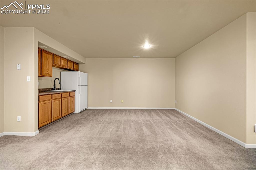 Image 29 of 40: This versatile living area features plush carpeting, recessed lighting, and