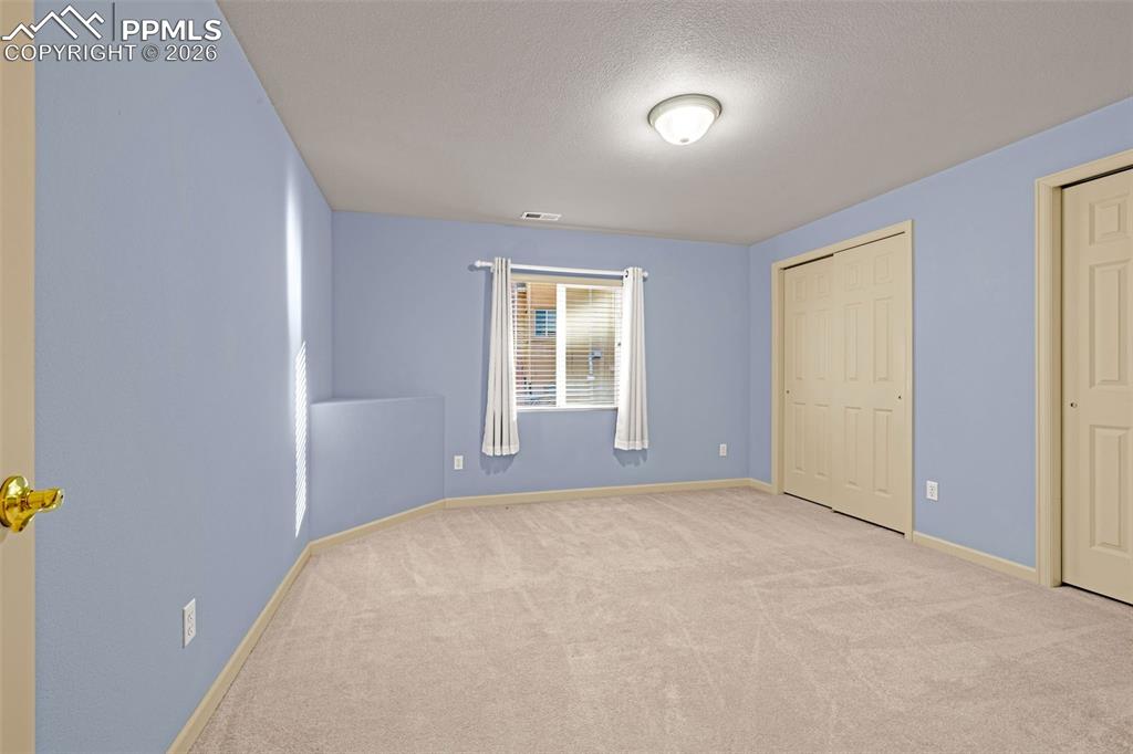 Image 30 of 40: This room features soft blue walls, a window with blinds and curtains, and 
