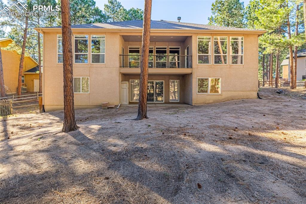 Image 33 of 40: The property features a  balcony on the upper level, surrounded by mature t