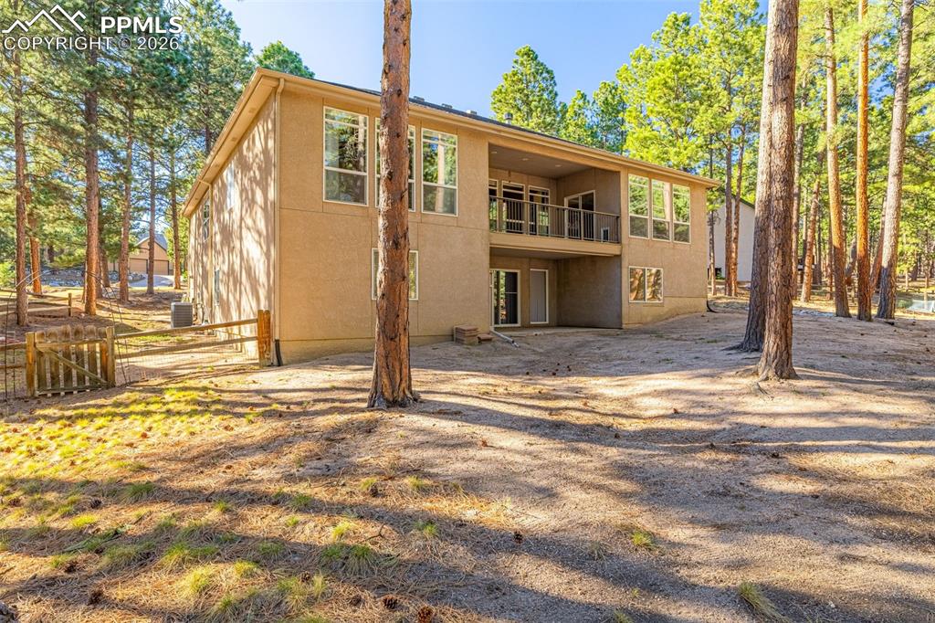 Image 34 of 40: TThe property features a  balcony on the upper level, surrounded by mature 