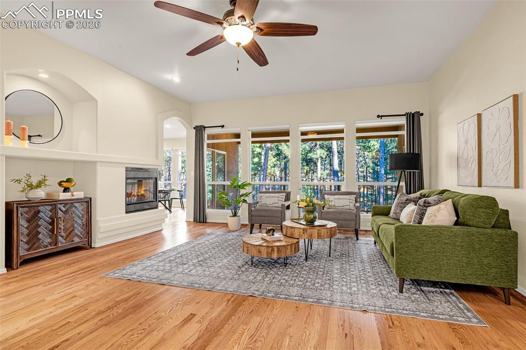 Image 4 of 40: The property features hardwood floors, a ceiling fan, and a fireplace with 
