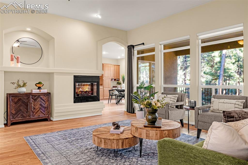 Image 6 of 40: Living room featuring hardwood floors, a double-sided fireplace, and large 