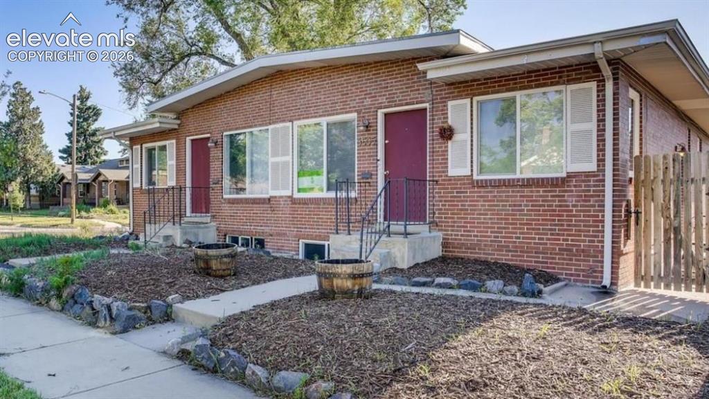 Image 1 of 1: Brick exterior with white window shutters and dark red entry doors