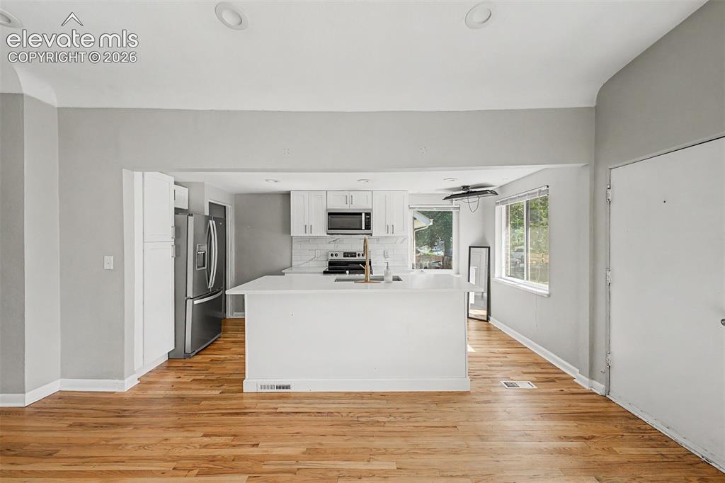 Image 10 of 40: Modern kitchen featuring an island with an undermount sink and brass faucet