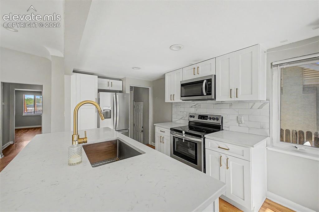 Image 13 of 40: Kitchen featuring a central island with white cabinetry, gold-toned hardwar