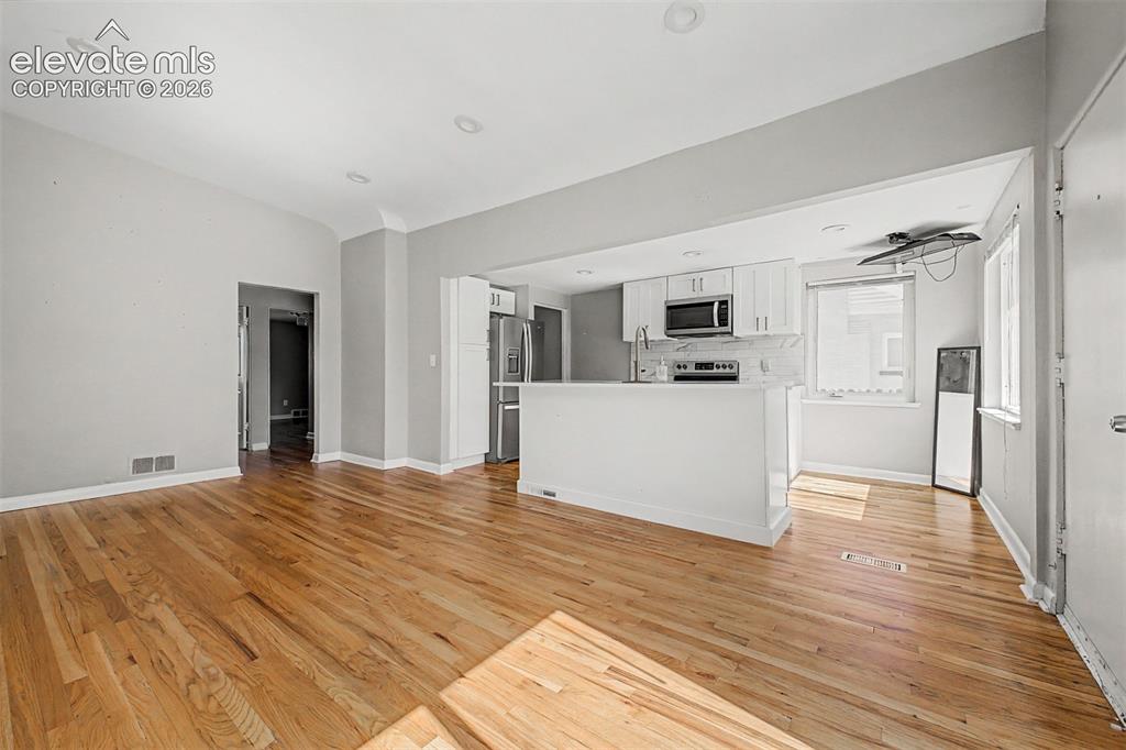 Image 9 of 40: Open-concept living space featuring wood-finish flooring, recessed lighting