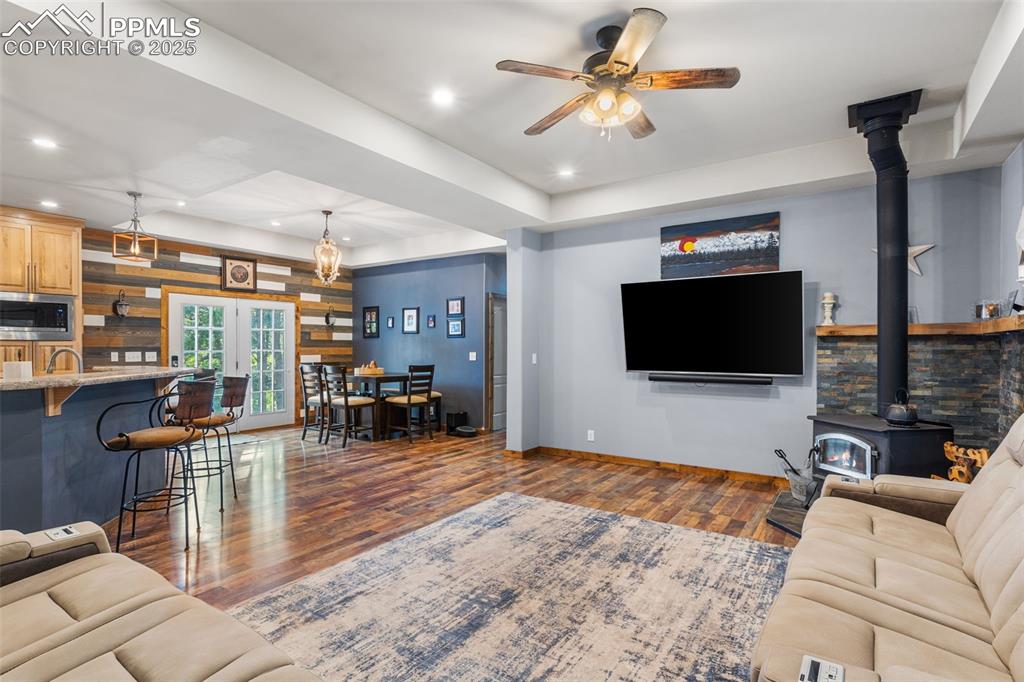Image 10 of 46: Living area with a wood stove, dark wood finished floors, a ceiling fan, re