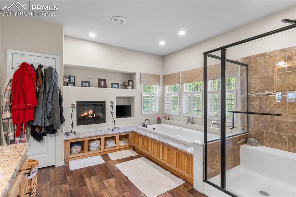 Image 15 of 46: Bathroom with a bath, a shower stall, wood finished floors, vanity, and rec