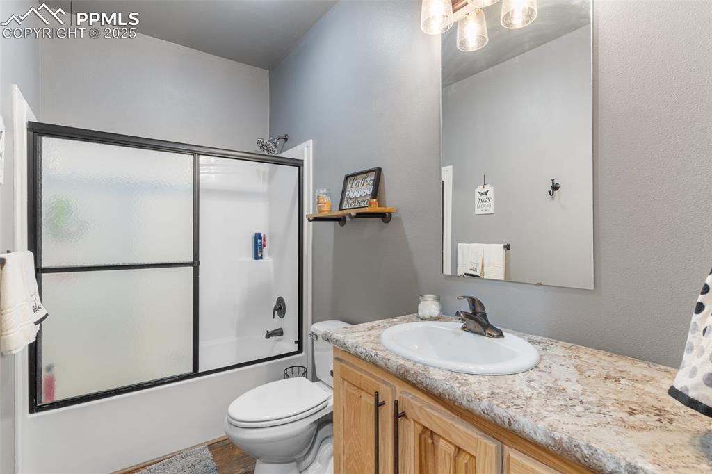 Image 18 of 46: Full bath featuring vanity, bath / shower combo with glass door, and wood f