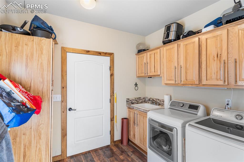 Image 23 of 46: Laundry area with independent washer and dryer, cabinet space, and dark woo