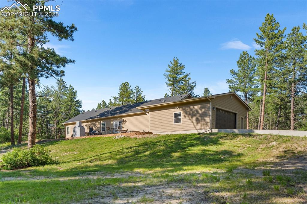 Image 36 of 46: View of side of home with a lawn, a garage, and driveway