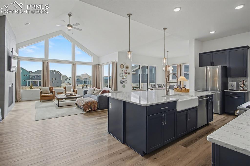 Image 15 of 39: Kitchen featuring open floor plan, a ceiling fan, light stone counters, sta