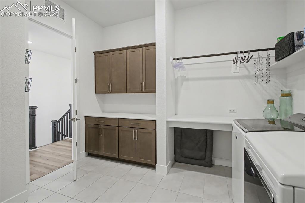 Image 21 of 39: Laundry room featuring washer and dryer, light tile patterned floors, and c