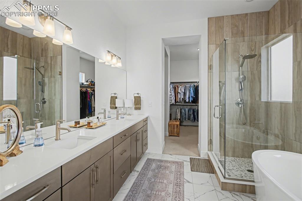 Image 24 of 39: Full bathroom featuring a spacious closet, a shower stall, double vanity, a