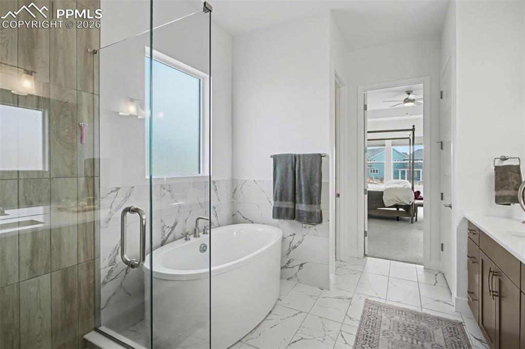 Image 25 of 39: Ensuite bathroom with vanity, a soaking tub, a marble finish shower, light 