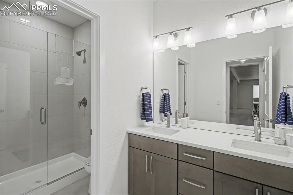 Image 29 of 39: Full bath with double vanity and a shower stall