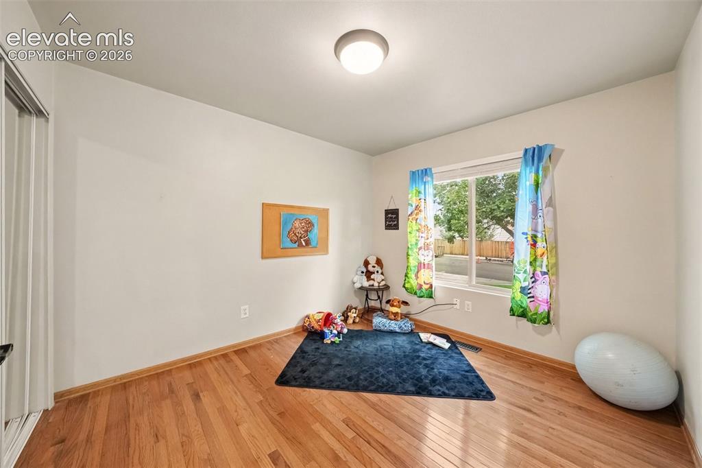 Image 13 of 28: The 2nd main-level bedroom features beautiful real wood flooring and plenty