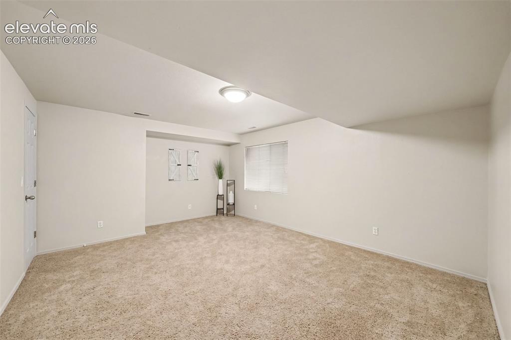 Image 19 of 28: The fourth basement bedroom features plush carpeting and a comfortable, inv