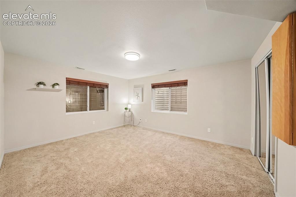 Image 21 of 28: The 5th basement bedroom features soft carpeting and a convenient built-in 