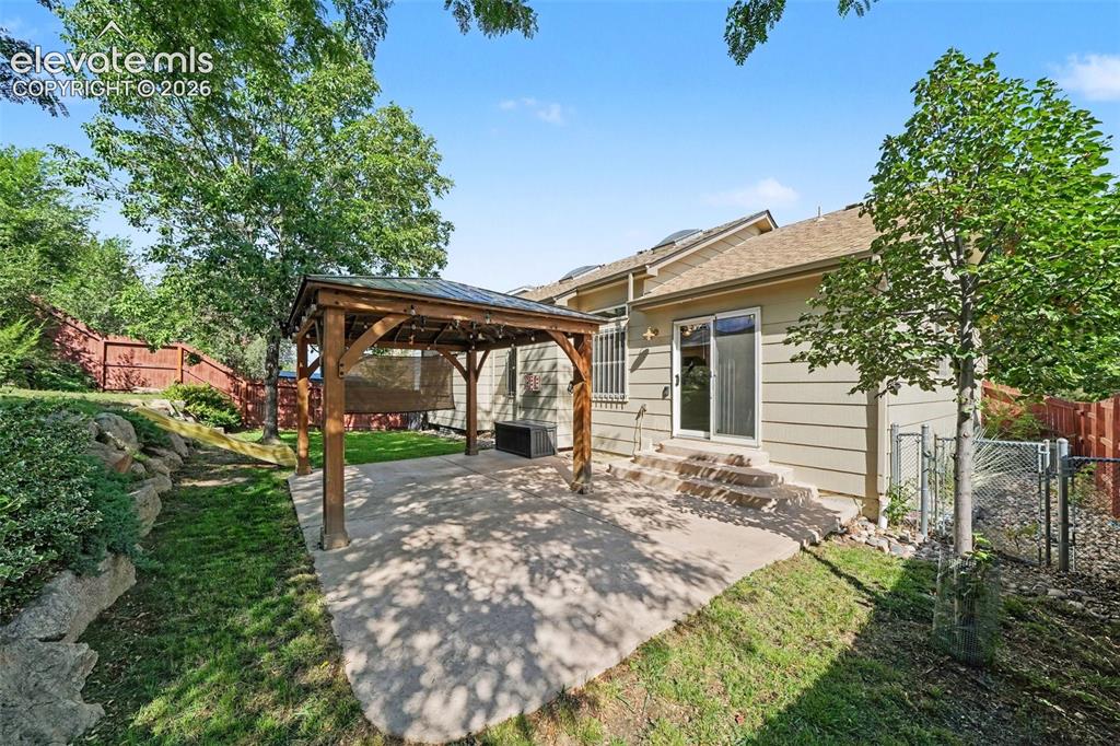 Image 25 of 28: The private backyard features a covered pergola accented with Edison-style 