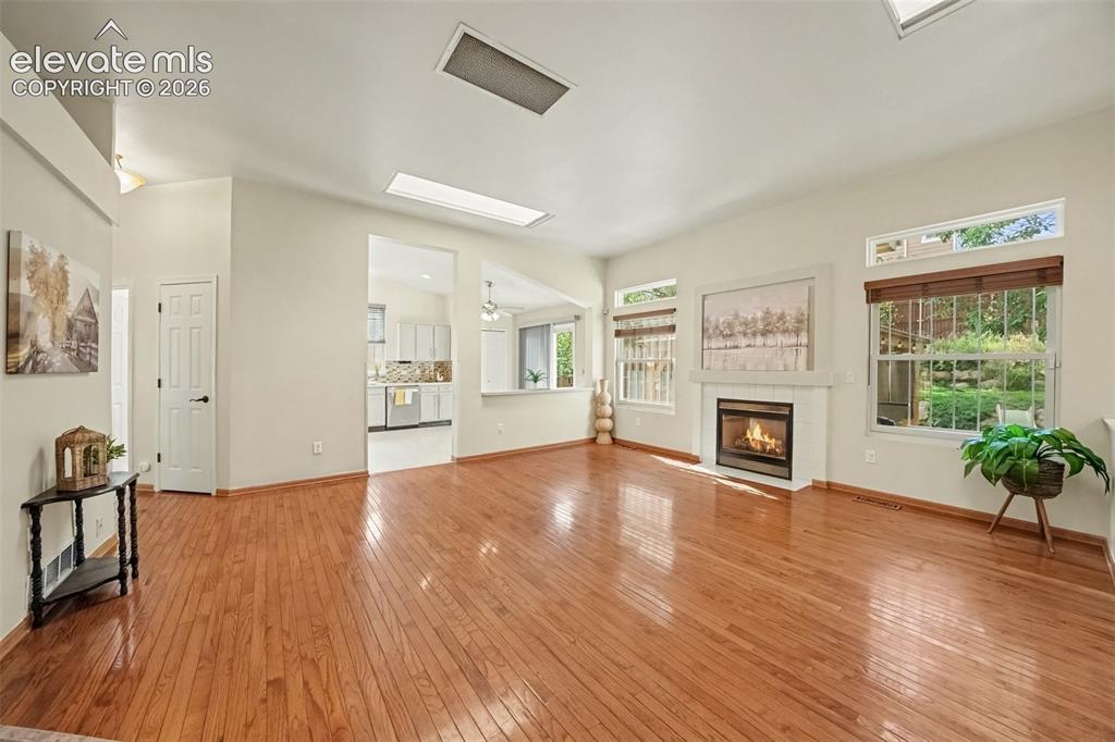 Image 4 of 28: The spacious living room features a cozy gas fireplace and skylights that f