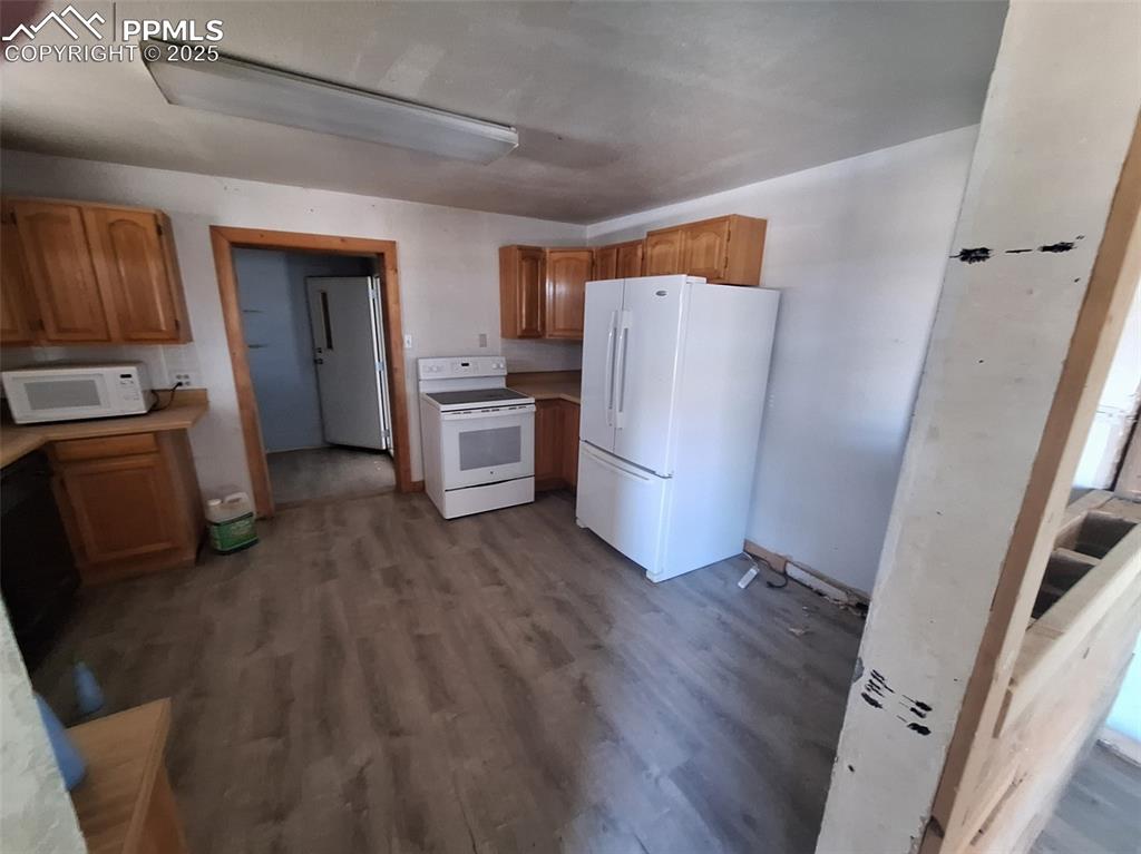 Image 2 of 24: Kitchen with white appliances, dark wood-type flooring, light countertops,