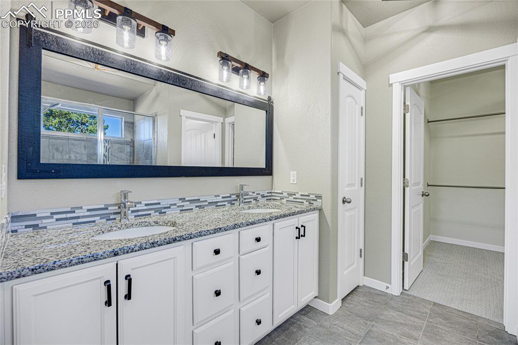 Image 16 of 50: The bathroom features a double vanity with white cabinetry, granite counter