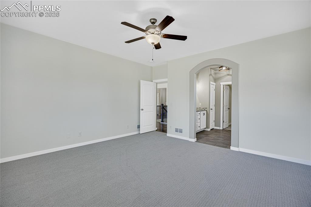 Image 26 of 50: This spacious room features light gray walls and carpeting, a ceiling fan w