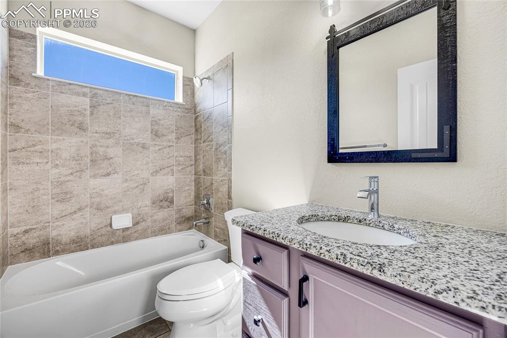 Image 30 of 50: The bathroom features a bathtub and shower with tile surround, a window, a 