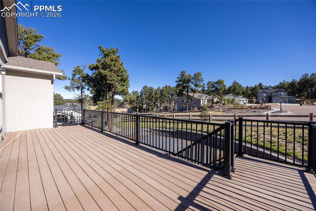 Image 34 of 50: Spacious outdoor deck with composite decking and black metal railings, offe