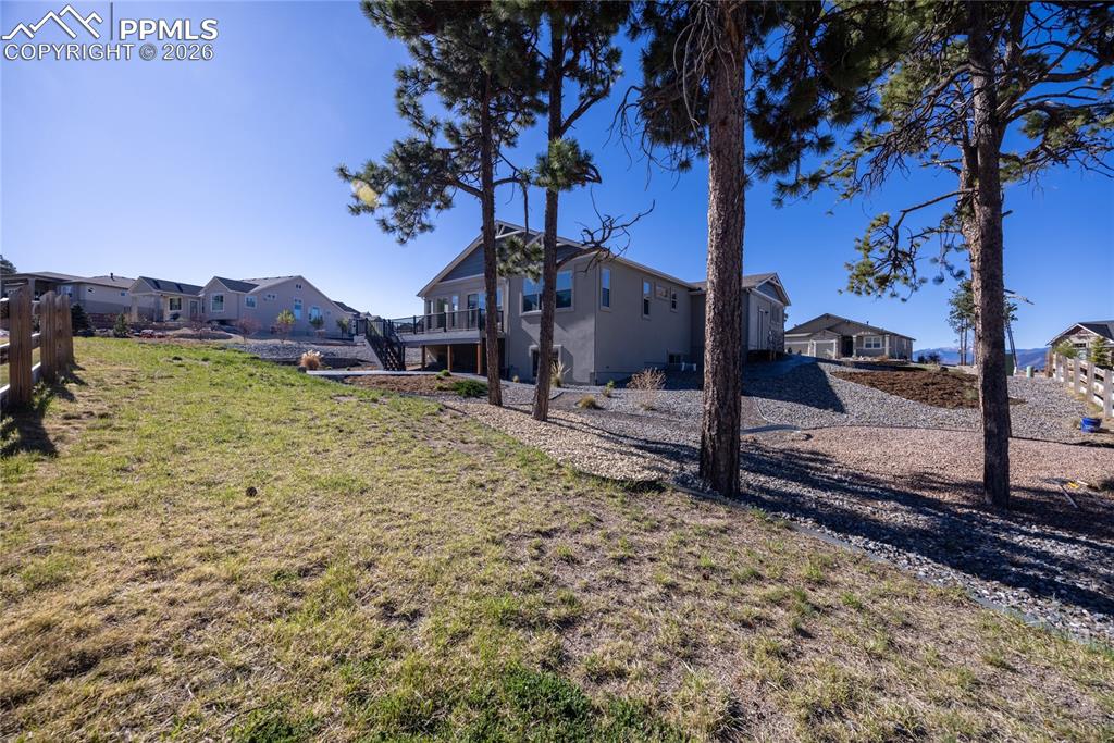 Image 37 of 50: The property features a spacious yard with a lawn, mature trees, and a wood