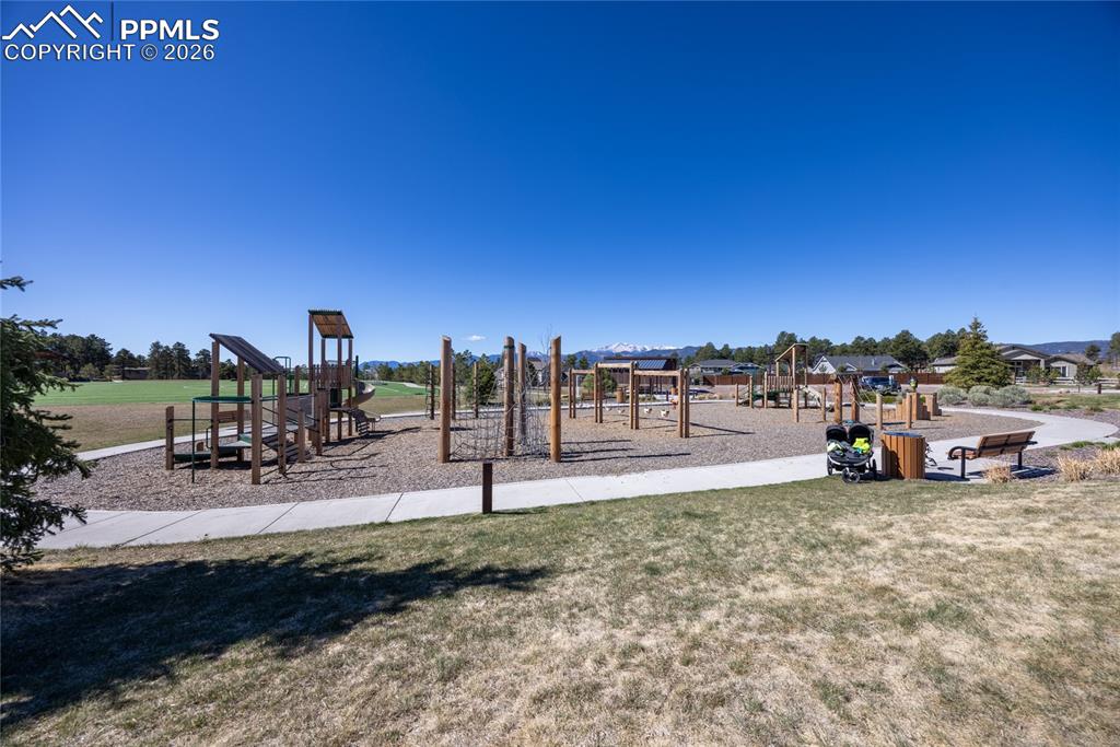 Image 40 of 50: Community playground featuring various wooden structures, surrounded by a p