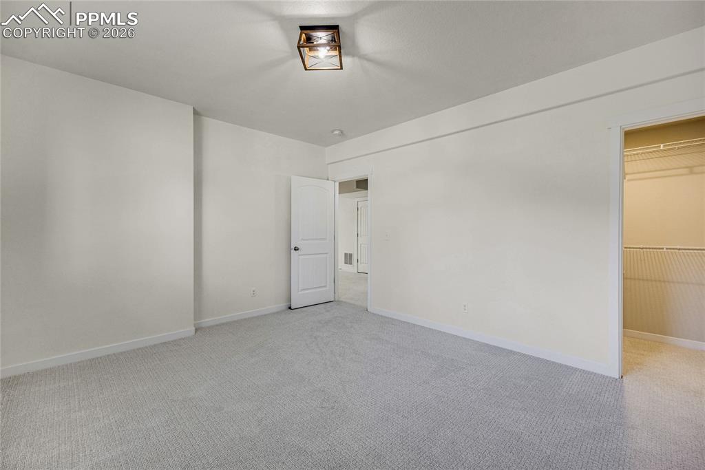 Image 46 of 50: This room features light-colored walls and carpeting, a ceiling-mounted lig