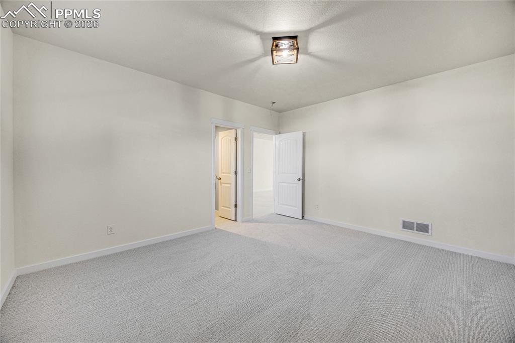 Image 48 of 50: The room features light-colored walls and grey carpet flooring