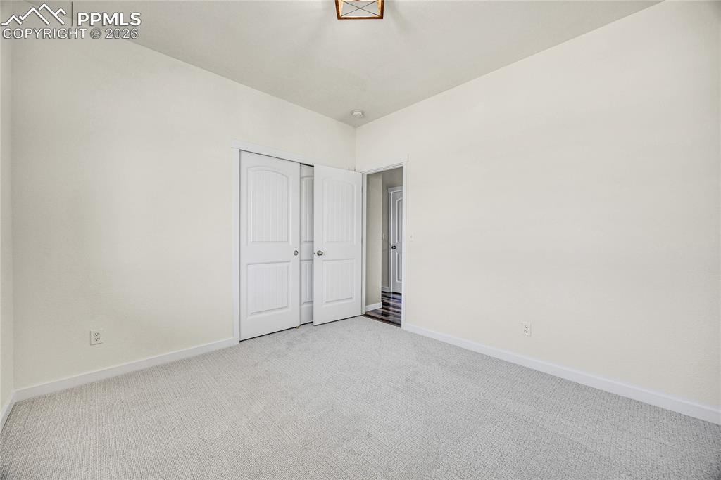 Image 50 of 50: This room features light-colored carpeting, white walls, and a sliding clos