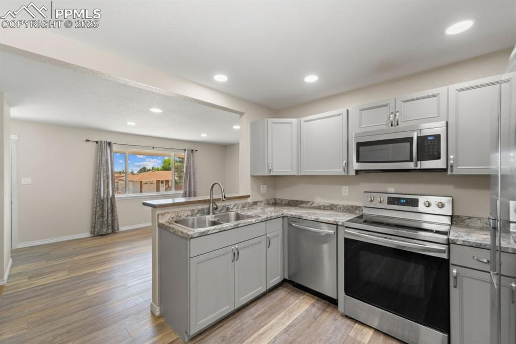 Image 13 of 48: Kitchen with appliances with stainless steel finishes, gray cabinets, reces