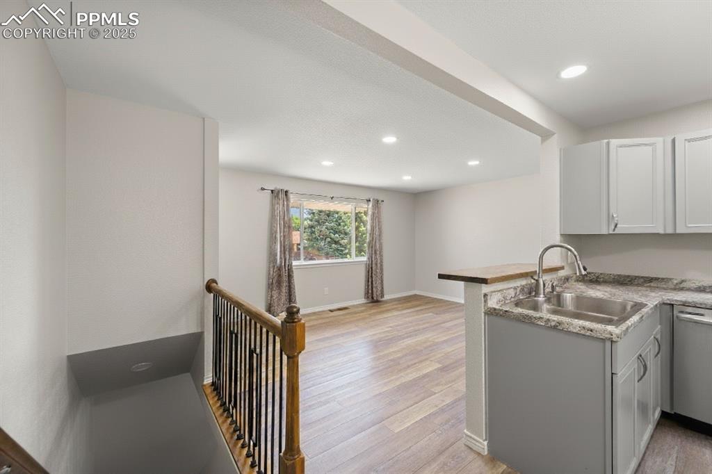 Image 15 of 48: Kitchen with light wood-type flooring, a peninsula, recessed lighting, gray