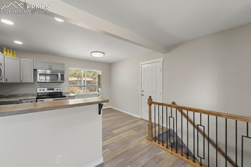 Image 17 of 48: Kitchen featuring gray cabinets, beamed ceiling, appliances with stainless 