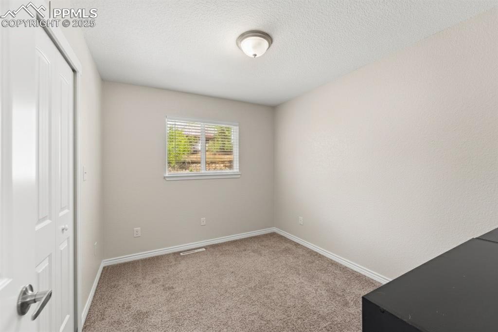 Image 22 of 48: Unfurnished bedroom with light carpet, a closet, and a textured ceiling