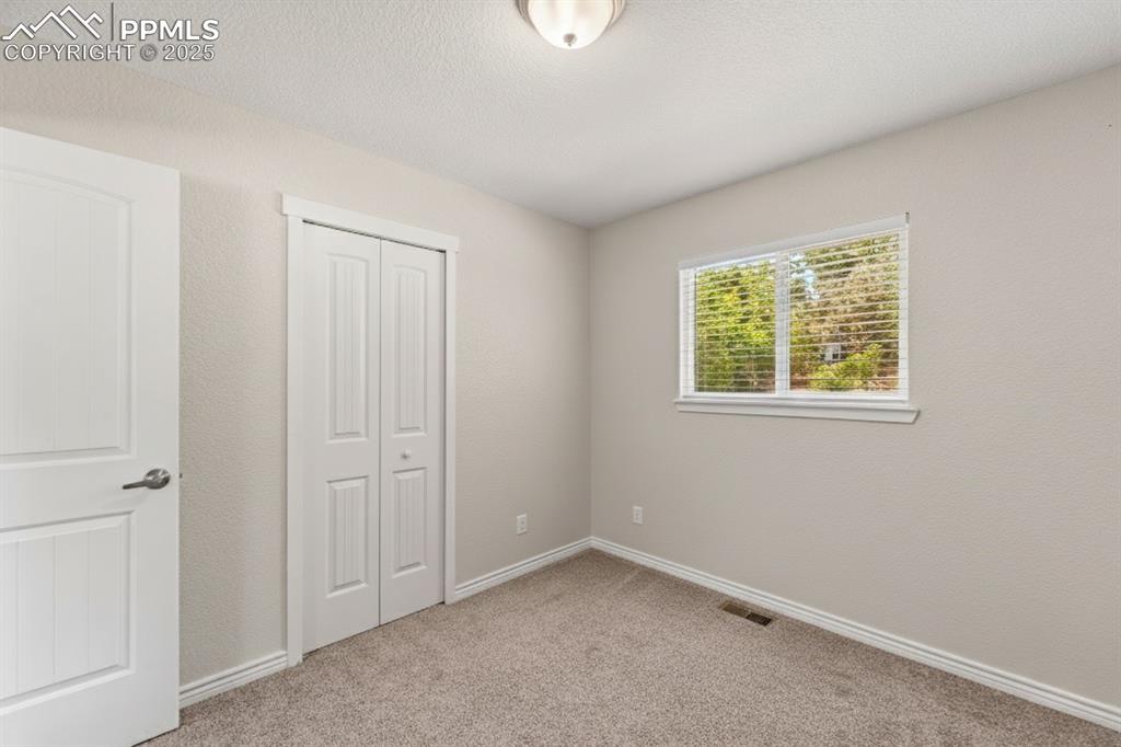 Image 23 of 48: Unfurnished bedroom featuring light colored carpet, a closet, a textured ce